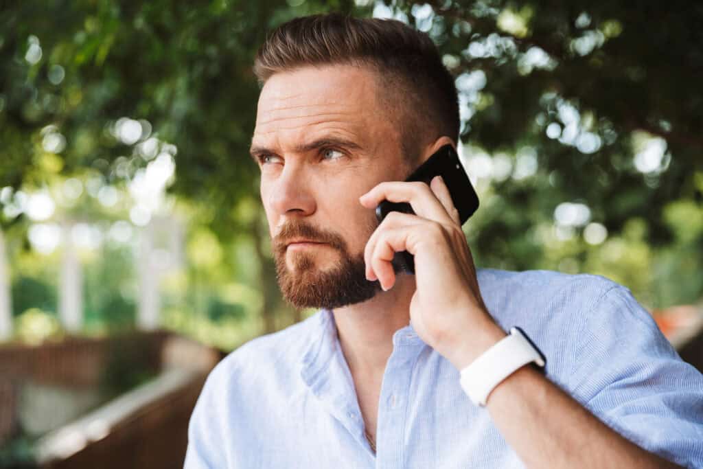 Close-up of a serious man talking on mobile outdoors, professional law firm in Arizona.