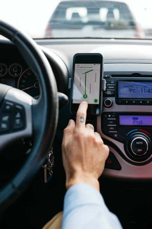 Driver using GPS navigation on smartphone inside car during ride-sharing.
